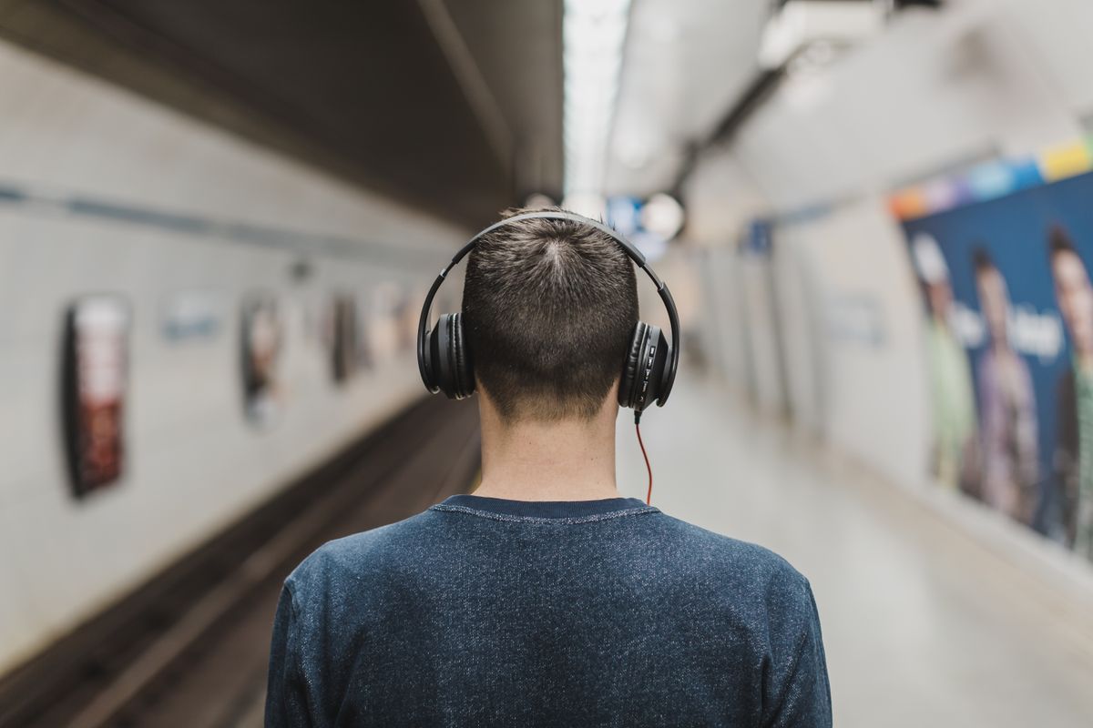 Persona escuchando música con auriculares en el metro